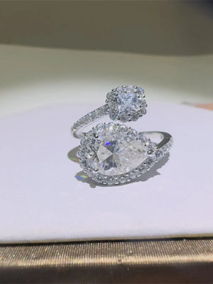 Silver bypass engagement ring with pear and square cut diamonds, halo setting.