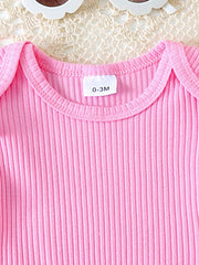 Pink ribbed cotton baby top with ruffle trim and daisy overalls detail