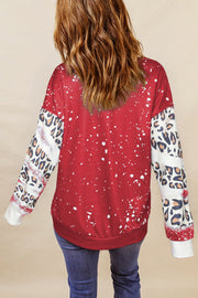 Red graphic sweatshirt with white splatter detail and leopard print sleeves.