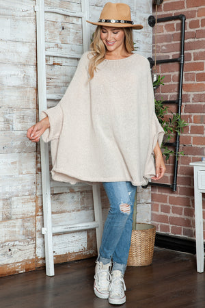 Cream knit cape sleeve sweater with wide batwing sleeves and a relaxed fit.