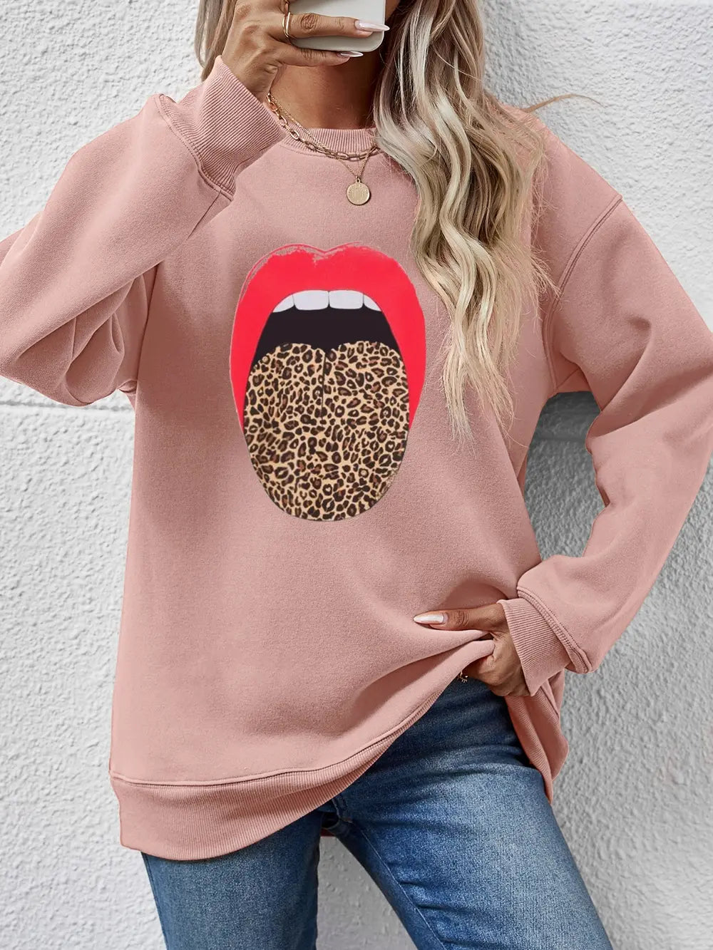 Blush pink sweatshirt with a bold red mouth and leopard print tongue graphic.
