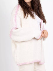 Oversized cream cardigan with contrast dusty pink trim details and a soft knit texture.