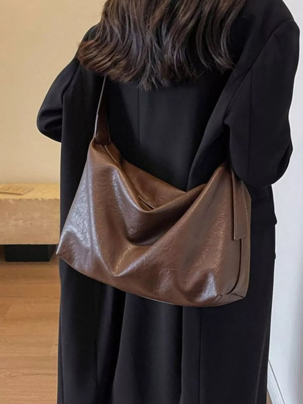 Brown faux leather shoulder bag with adjustable strap and slouchy design.