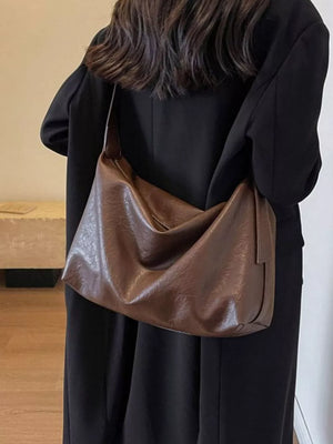 Brown faux leather shoulder bag with adjustable strap and slouchy design.