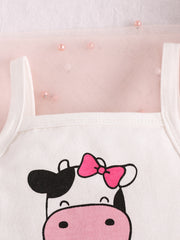 Baby cotton tank with cow print and pink bow detail, layered over sheer pink fabric with pearls.