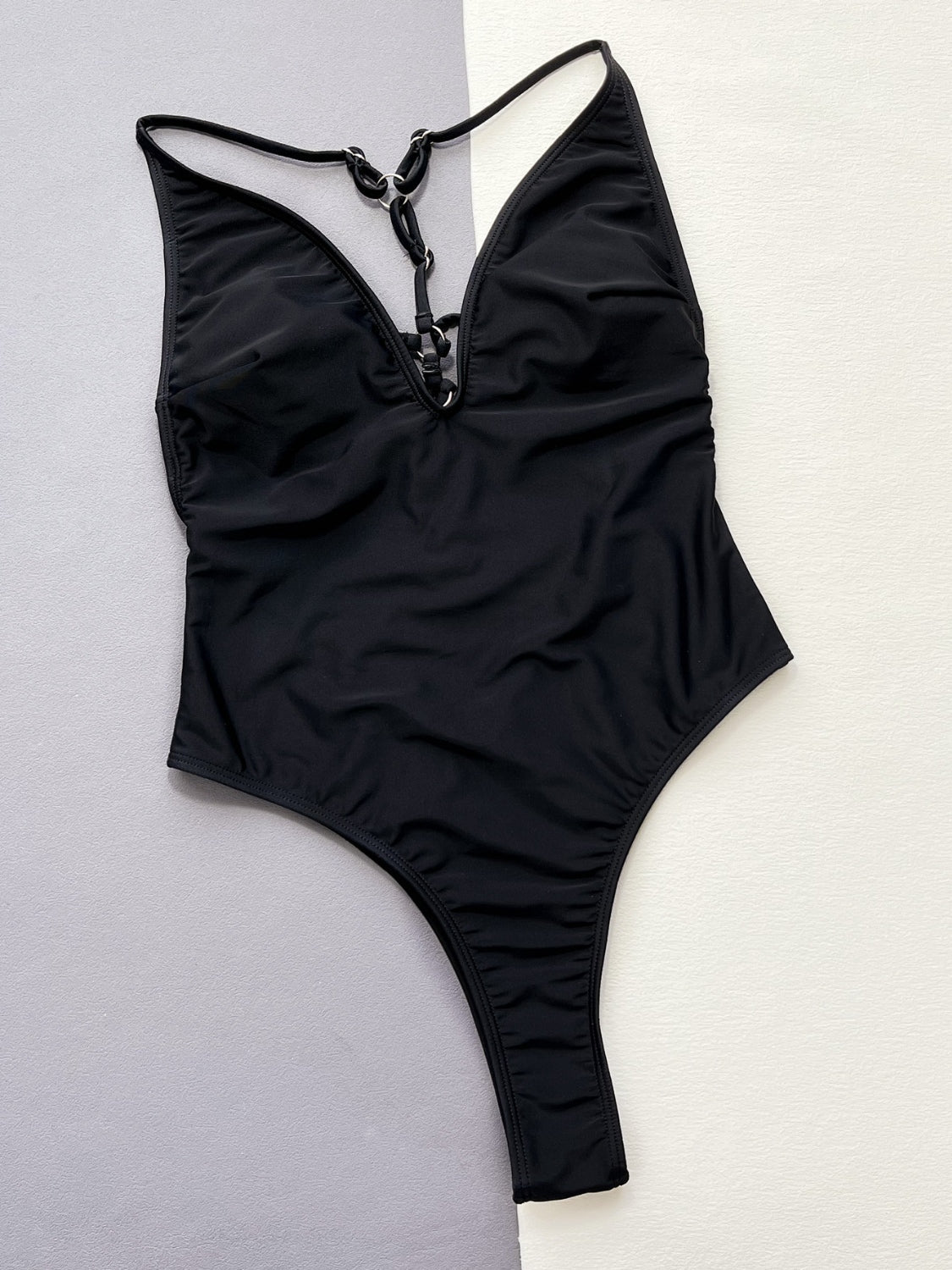 Black one-piece swimsuit with plunging neckline and ring detail.