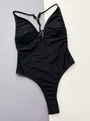 Black one-piece swimsuit with plunging neckline and ring detail.