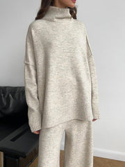 Oversized beige turtleneck lounge set with wide-leg pants and ribbed cuffs and hem.