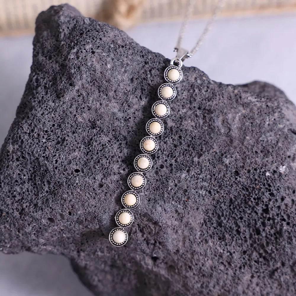 Delicate white beaded pendant necklace with alloy setting on a chain.
