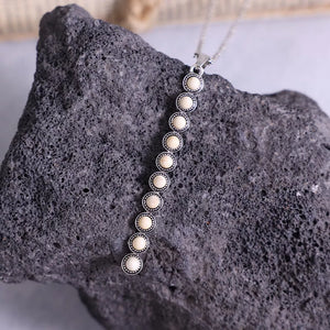 Delicate white beaded pendant necklace with alloy setting on a chain.