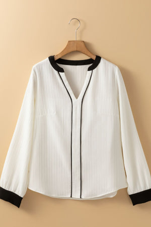 White textured V-neck blouse with black trim and cuffs.