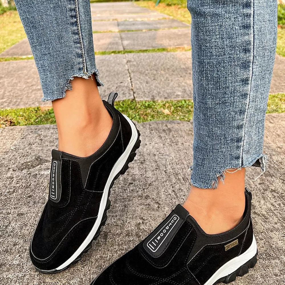 Black suede-like round toe slip-on sneakers with "OUTDOOR" detail and white soles.