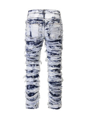 Distressed shredded denim jeans in medium sculptural wash with artistic rips and fraying.