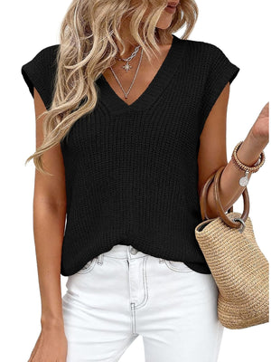 Textured black V-neck sweater vest with short sleeves, styled with white jeans and a straw bag.