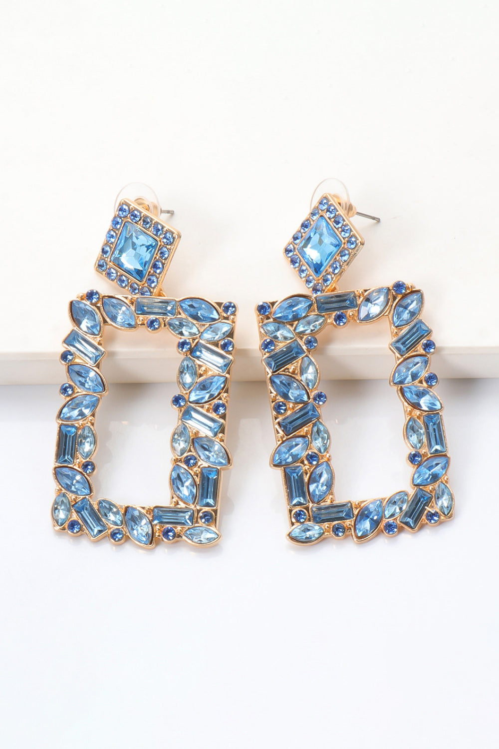 Geometric jewel box earrings with blue stones and gold alloy frames.