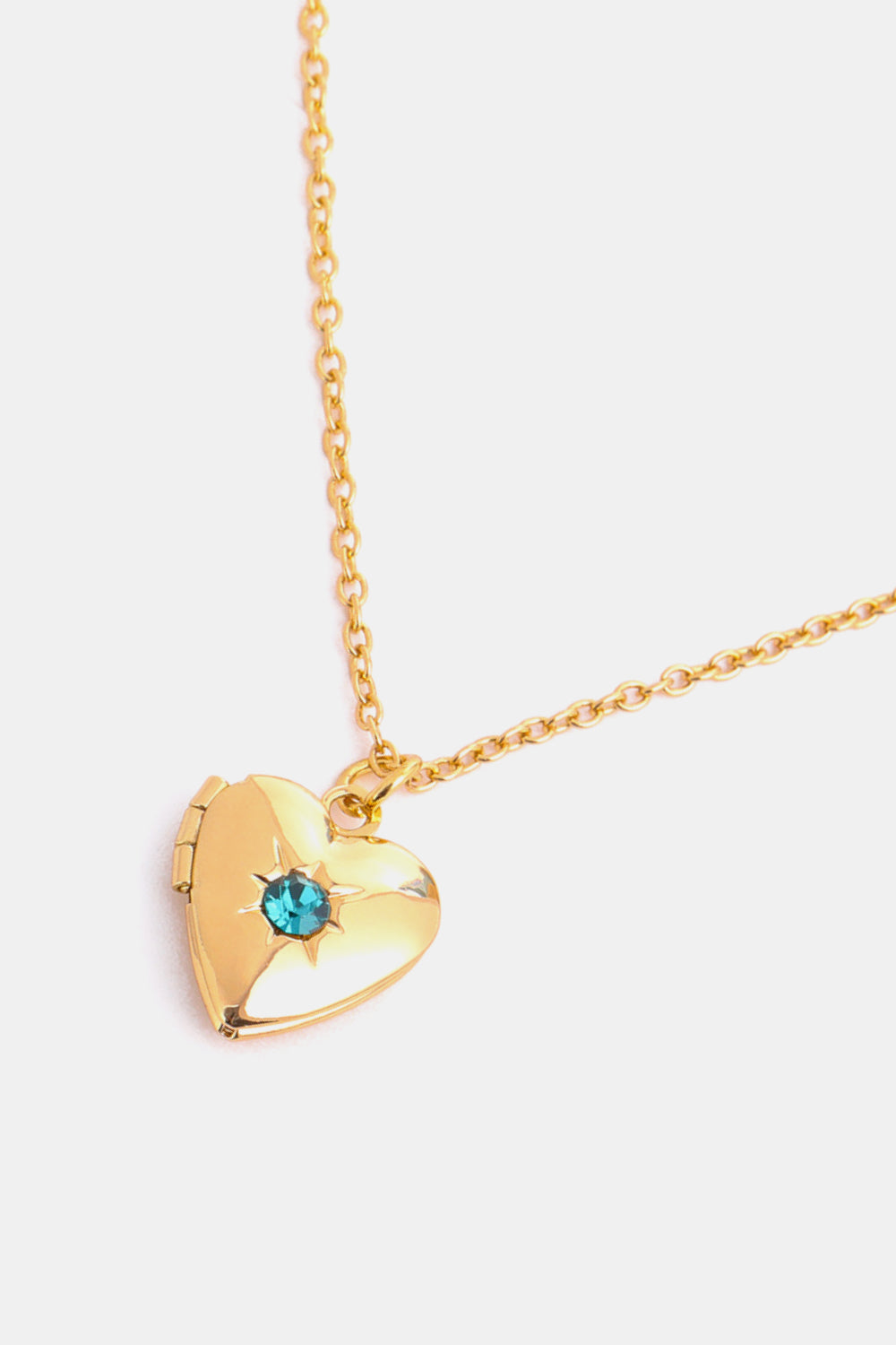 Gold heart locket necklace with blue gemstone and starburst detail on a delicate chain.