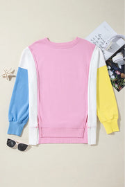 Colorblock sweatshirt in blush pink, white, blue, and yellow with split hem detail.