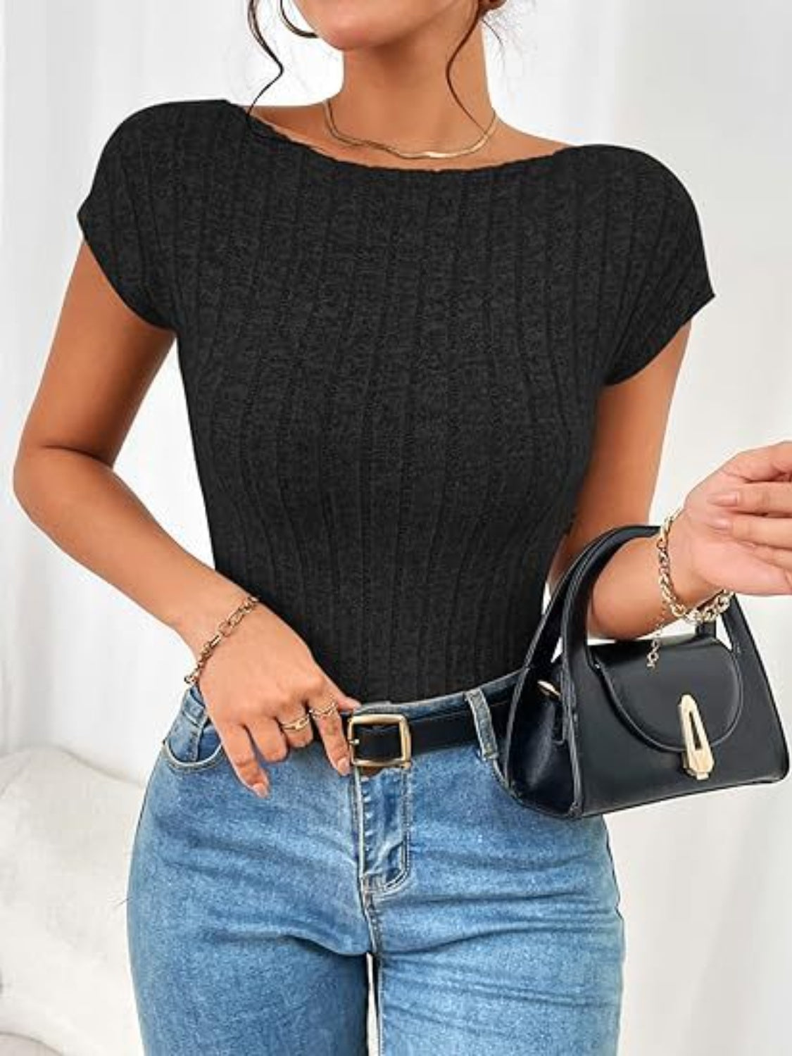 Black ribbed knit top with short sleeves and a boat neckline, styled with jeans and a handbag.
