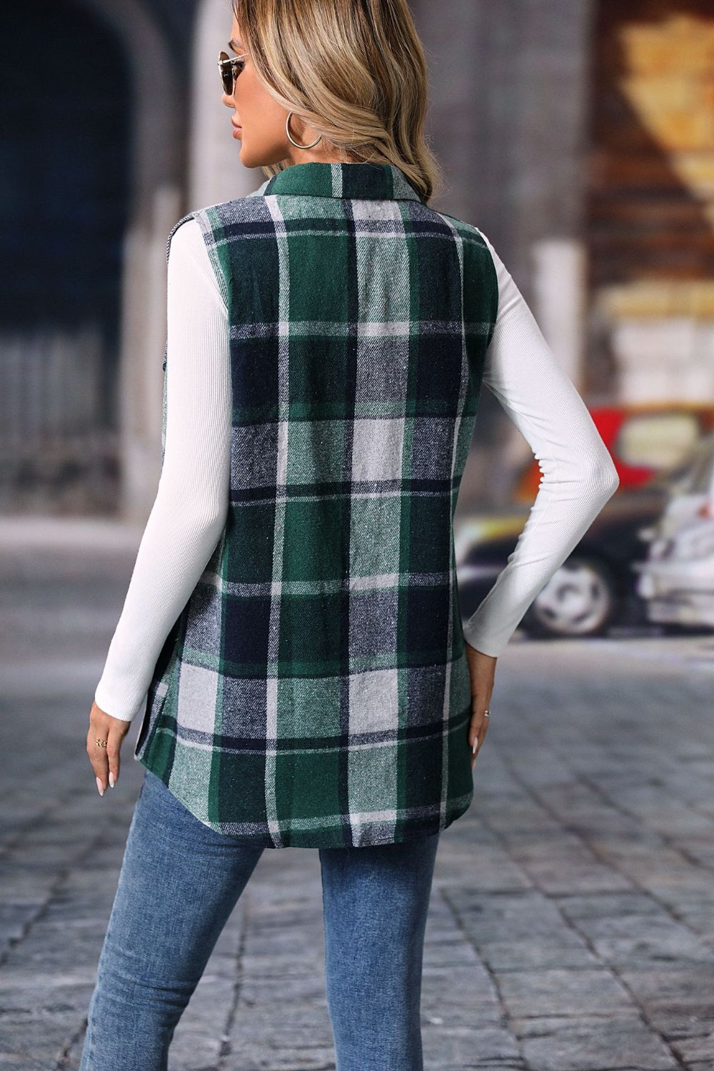 Plaid utility vest in dark green with button detail, worn over a white long-sleeve shirt.