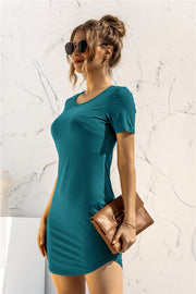 Turquoise crewneck bodycon dress with short sleeves, styled with sunglasses and a clutch.