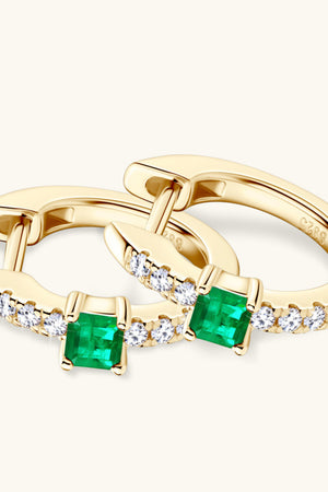 Gold huggie hoop earrings with emerald and pave diamond details.