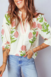 Vibrant floral cotton blouse with ruffled sleeves and notched neckline.