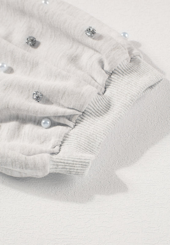 Light gray sweatshirt with pearl and rhinestone embellishments on puff sleeves and ribbed cuffs.