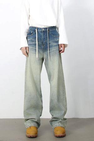 Faded wash wide-leg jeans with drawstring waist and light blue to pale green gradient.