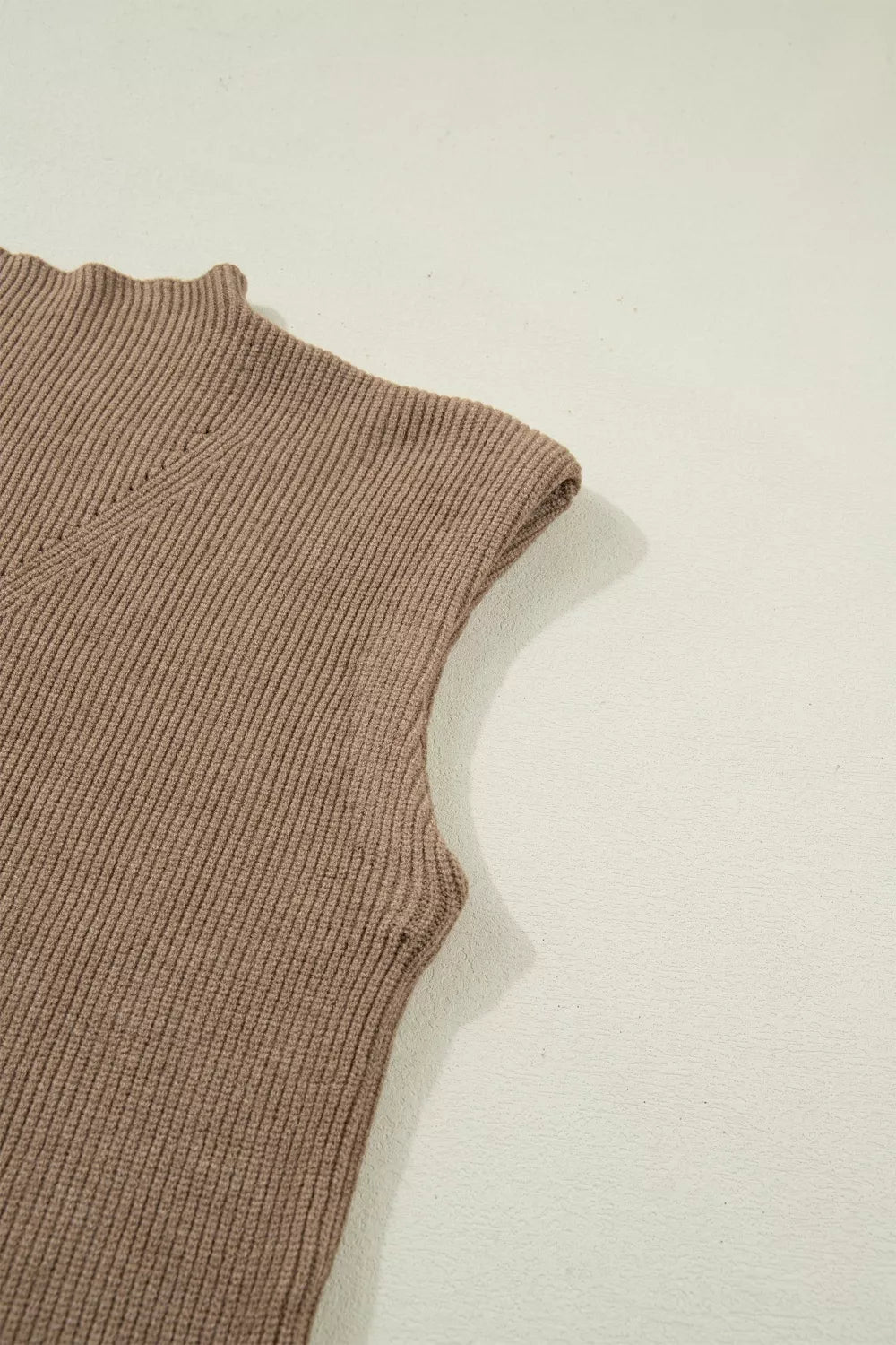Brown ribbed knit mock neck sweater vest with lettuce edge detail.