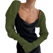 Army green ribbed knit shrug with extended sleeves worn over a black slip dress.