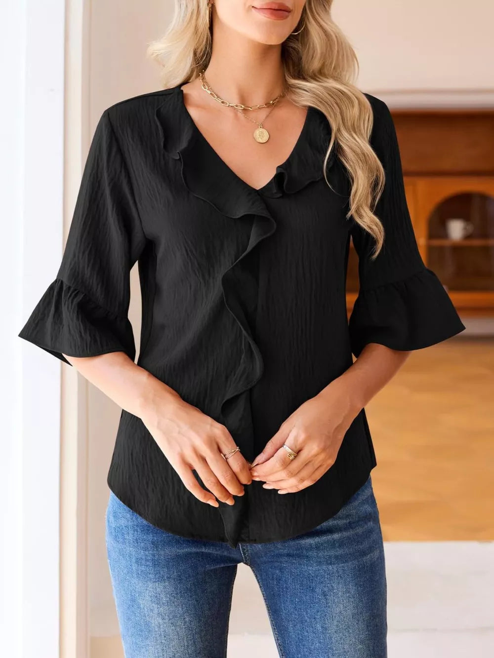 Black maternity shirt with V-neck, cascading ruffles, and 3/4 bell sleeves.