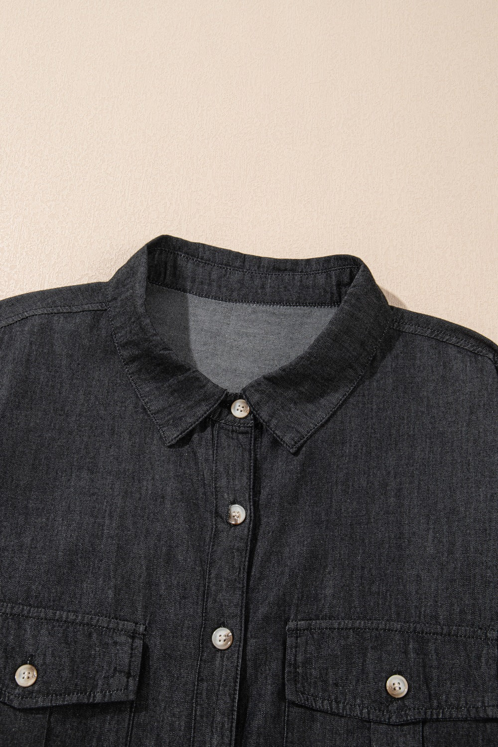 Relaxed black denim shirt with buttoned patch pockets and collar detail.