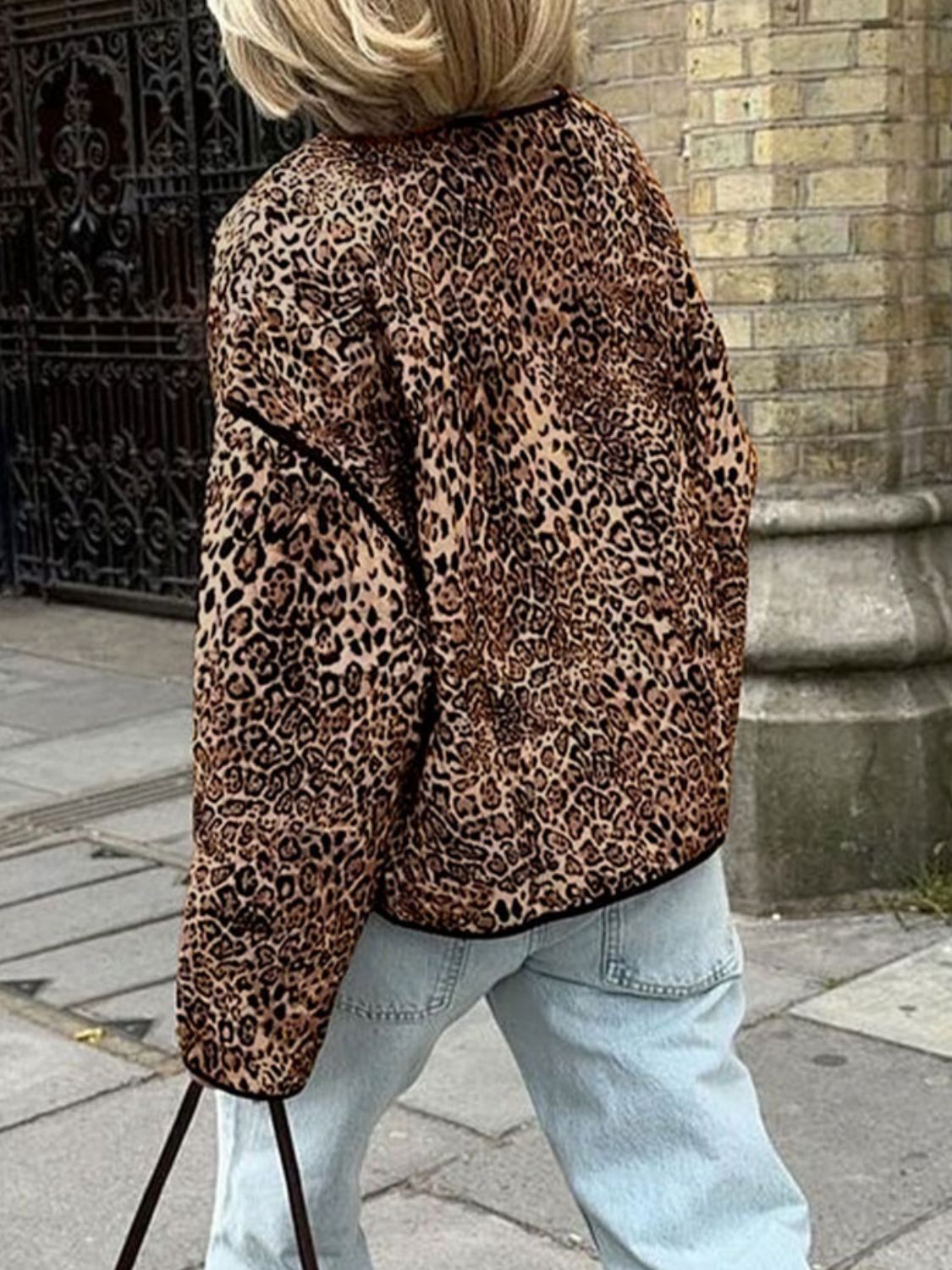 Leopard print boxy jacket with black edge trim, worn by a woman in light wash jeans.
