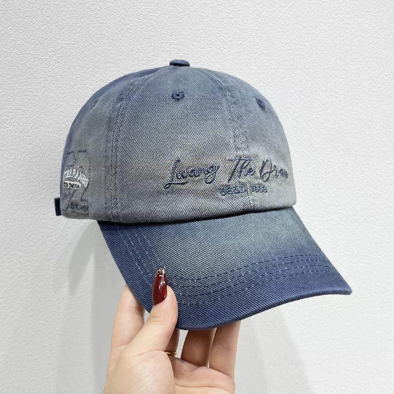 Gradient embroidered cotton baseball cap in dark blue with script text detail.