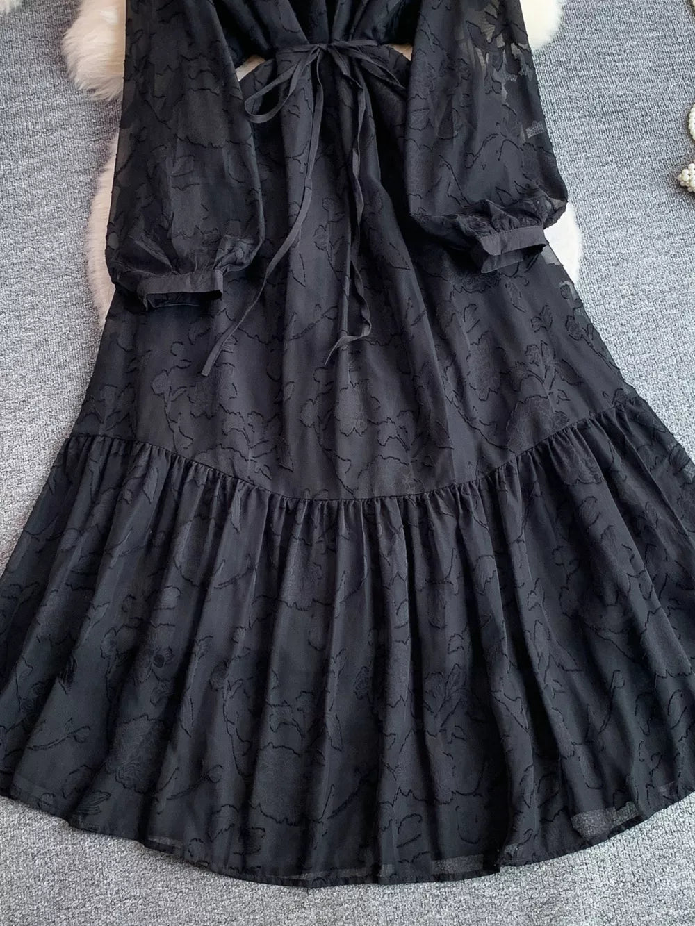 Black embroidered tie-waist dress with sheer sleeves and tiered skirt.