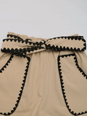Tan paperbag shorts with scalloped black trim and a tie waist.