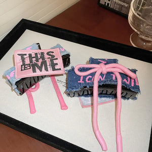 Denim patchwork claw clip with pink drawcord and text detail.