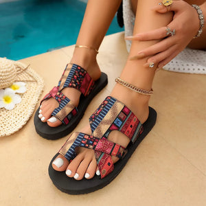 Toe loop sandals with colorful geometric pattern straps and black soles.