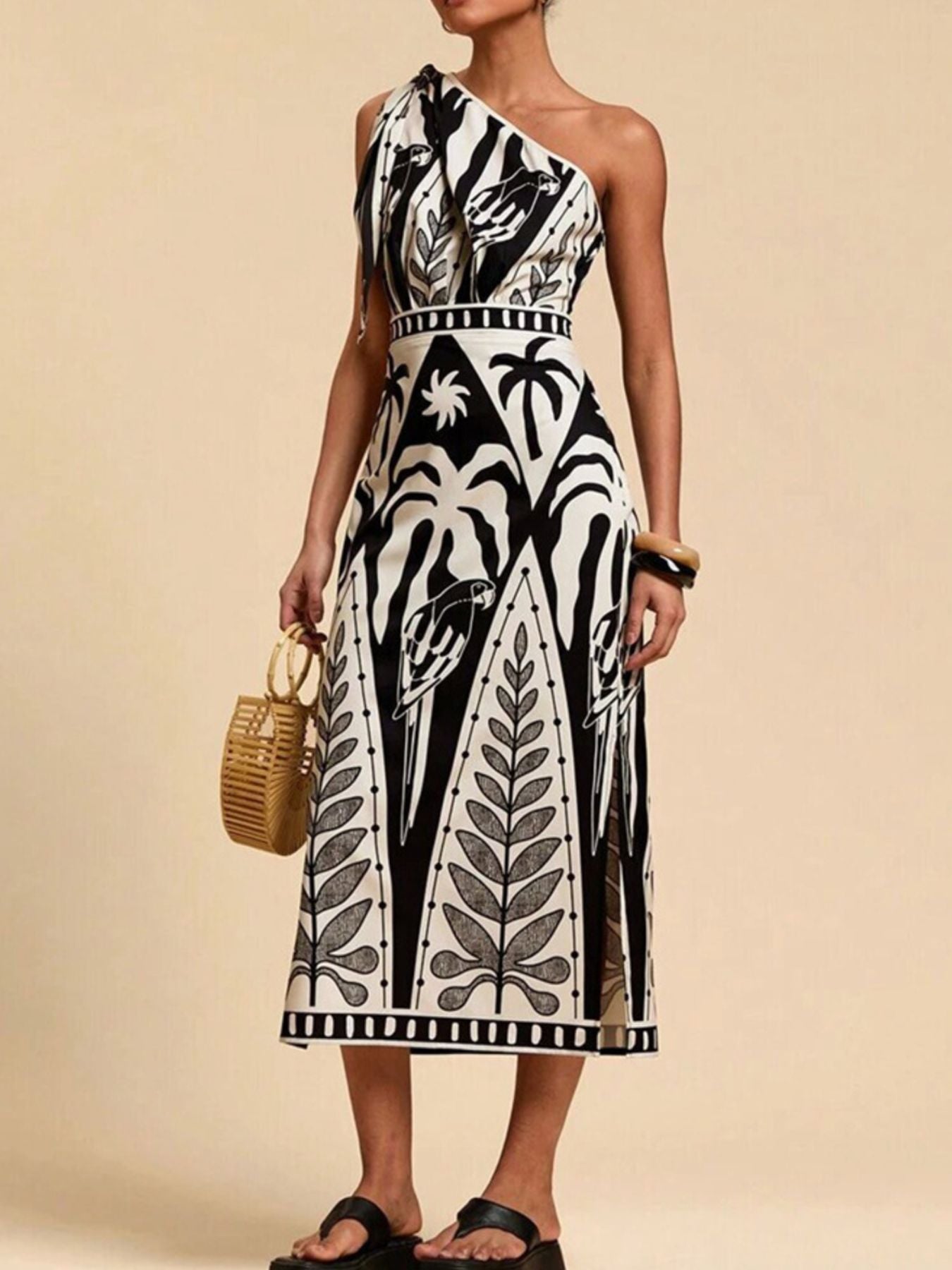 Tropical print one-shoulder midi dress with defined waist and side slits.