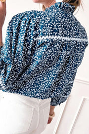 Peacock blue medallion print poet blouse with ruffled collar and white trim detail.