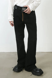 Black denim trousers with flared leg and seam detail, styled with a belt.