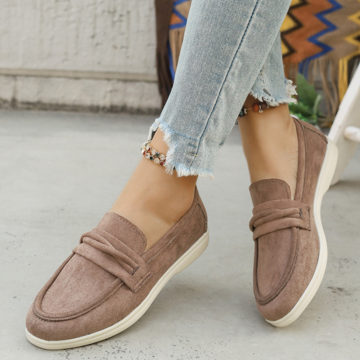 Beige slip-on loafers with ruched detail and white soles.