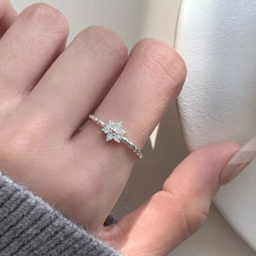 Twisted band sterling silver ring with a delicate zircon flower design.