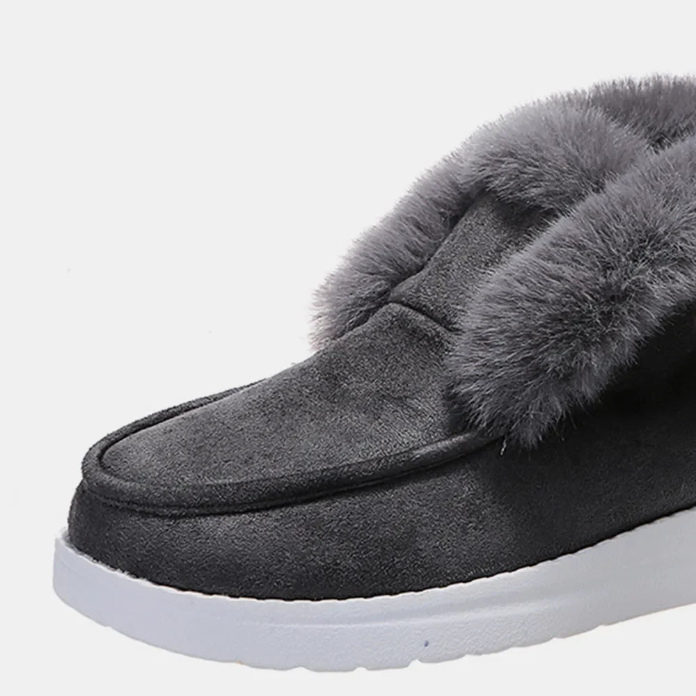 Dark gray suede slip-on booties with plush shearling lining and white sole.