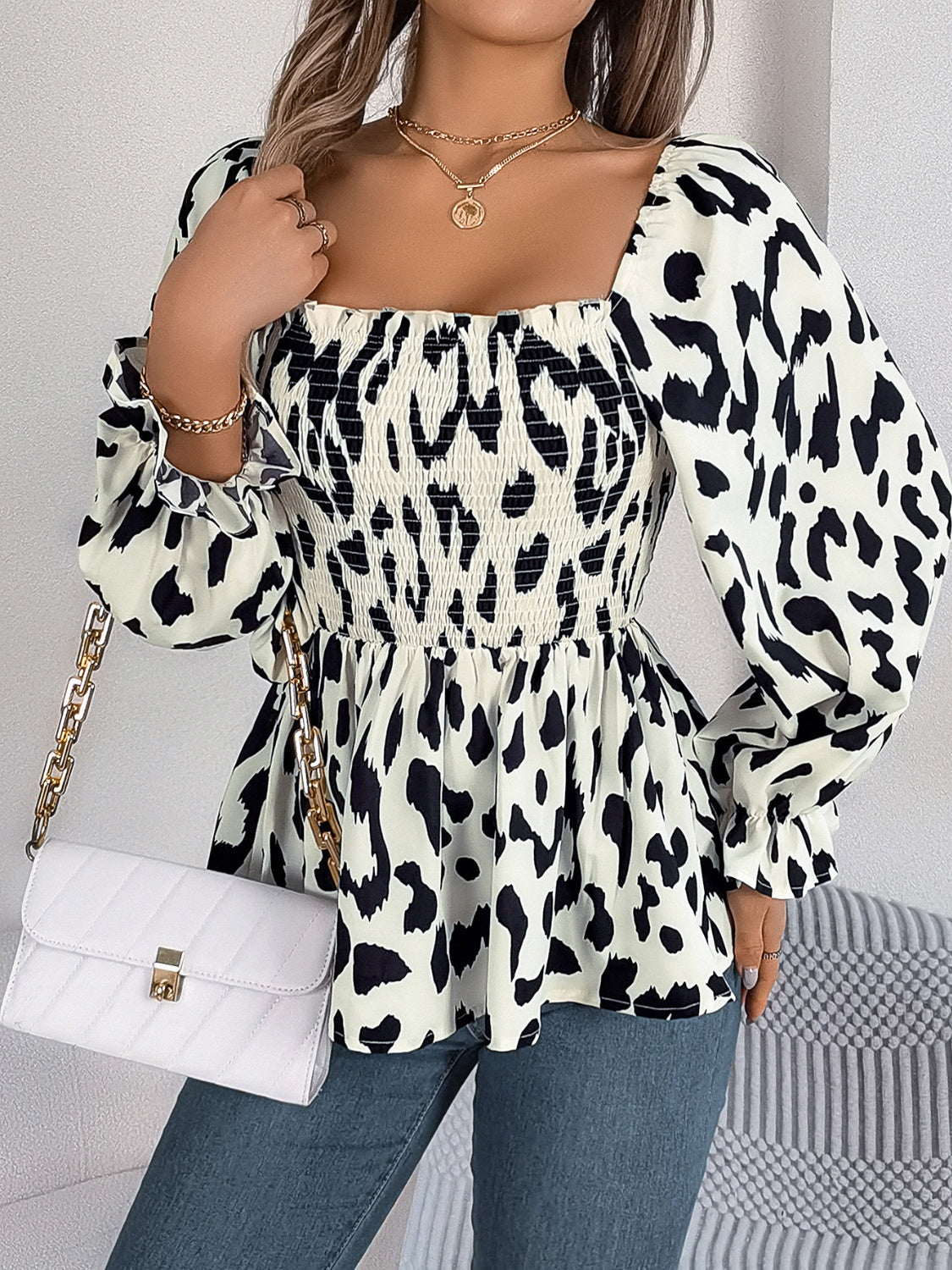 Cream and black leopard print smocked bodice square neck peplum blouse with ruffled cuffs.