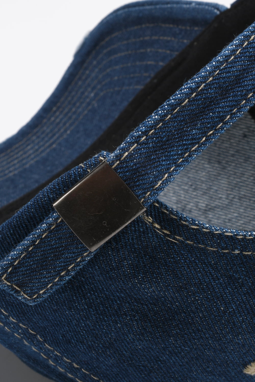 Denim baseball cap in dark navy with adjustable strap and metal buckle detail.
