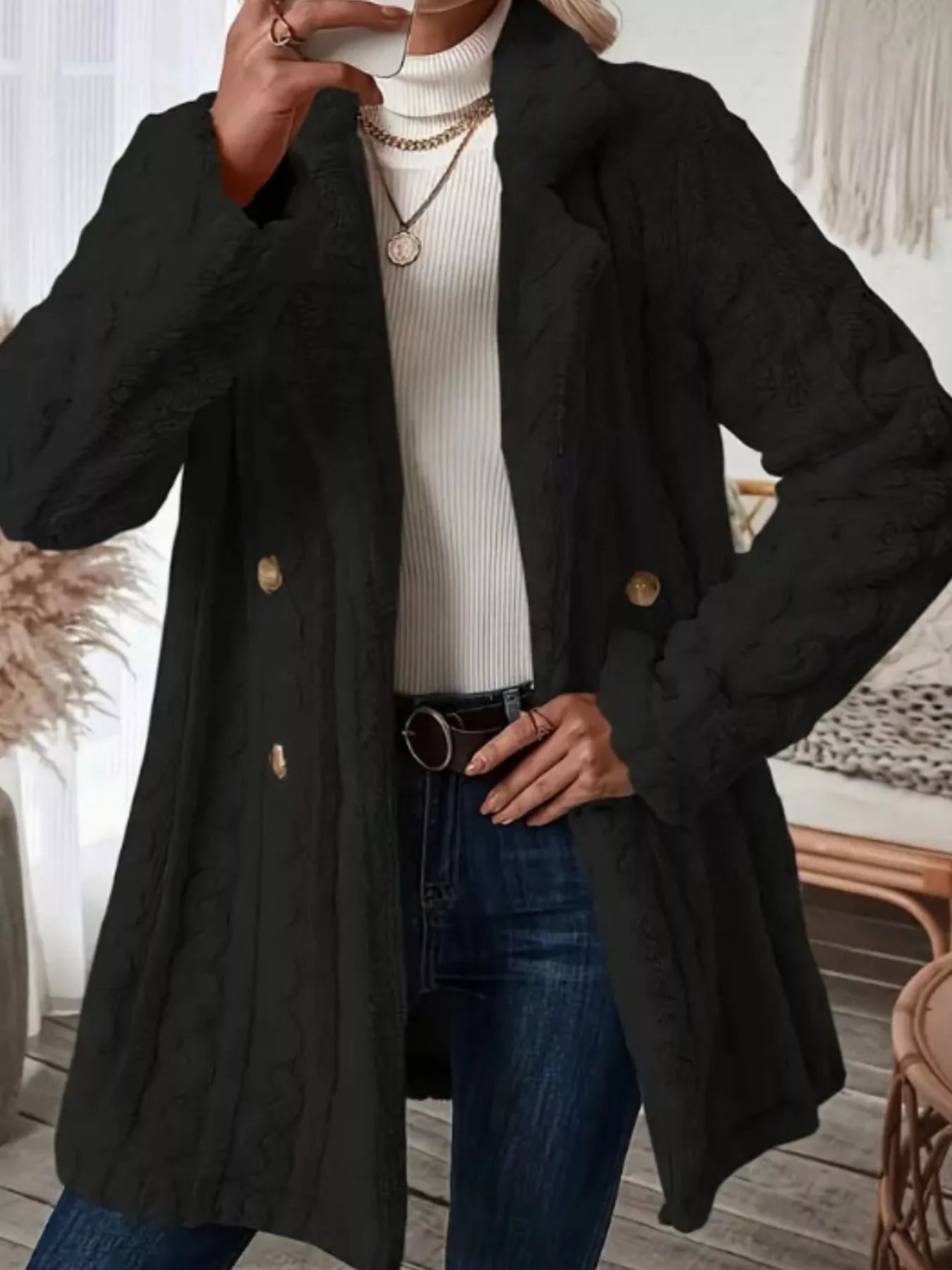Black faux shearling double-breasted overcoat with cable knit texture and gold buttons.