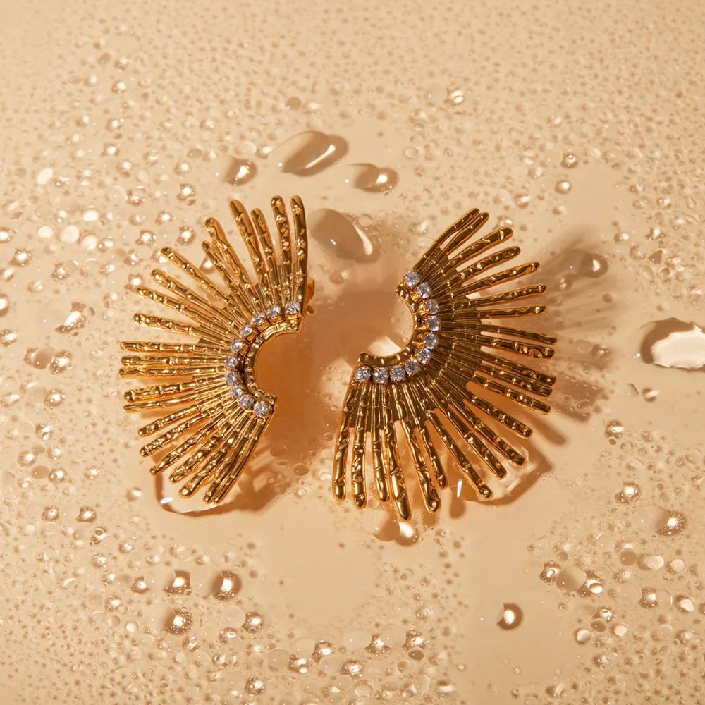 Gold sunburst crystal earrings with textured rays and a sparkling crystal arc.