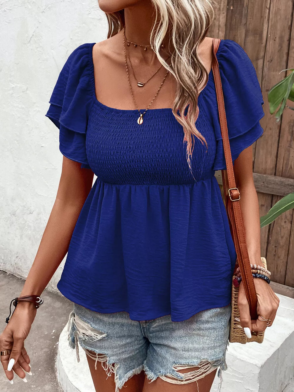 Blue textured smocked blouse with square neckline and ruffled sleeves.