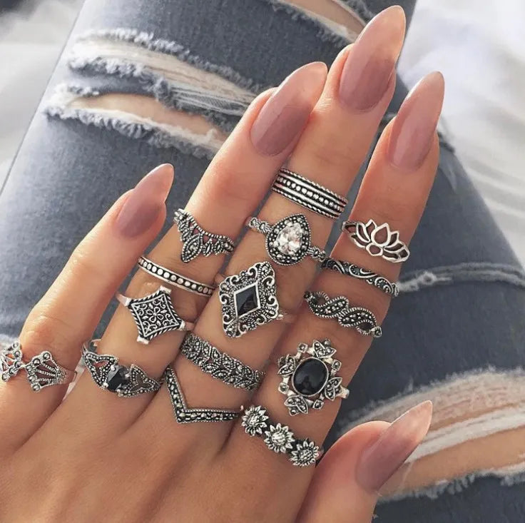 Bohemian silver rings with intricate designs, including lotus and floral motifs, on a hand with long nails.
